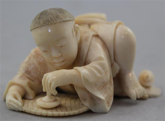 A Japanese carved ivory okimono of a child with a spinning top, 19th century, 17.6cm